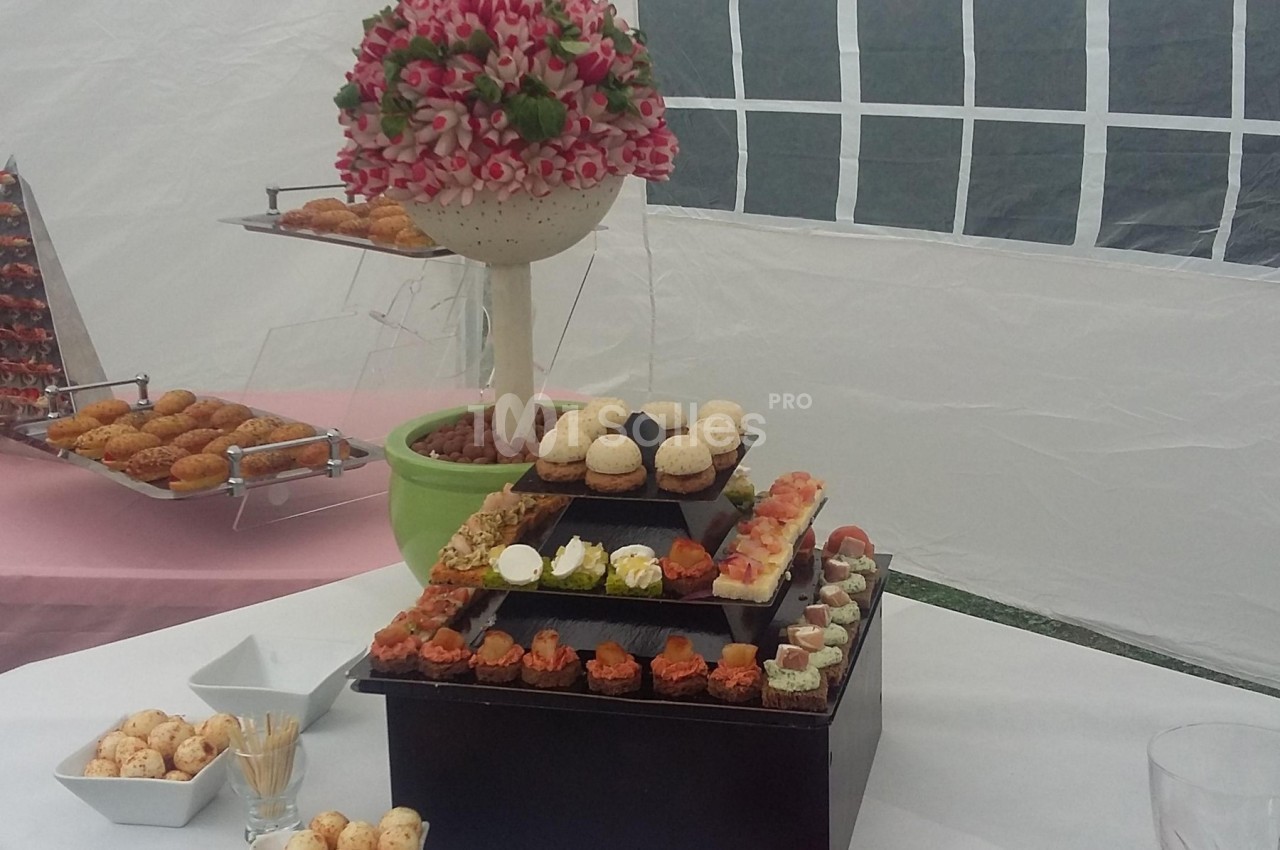 Plateau de mignardises variées disposées sur plusieurs niveaux, avec une décoration florale en arrière-plan.