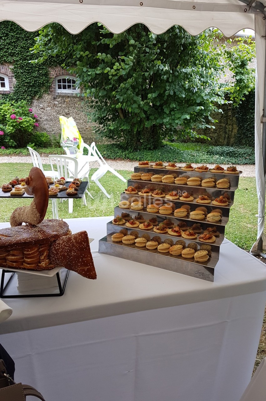 Plateau de petits fours variés disposés sur une table blanche, en extérieur sous une tente.