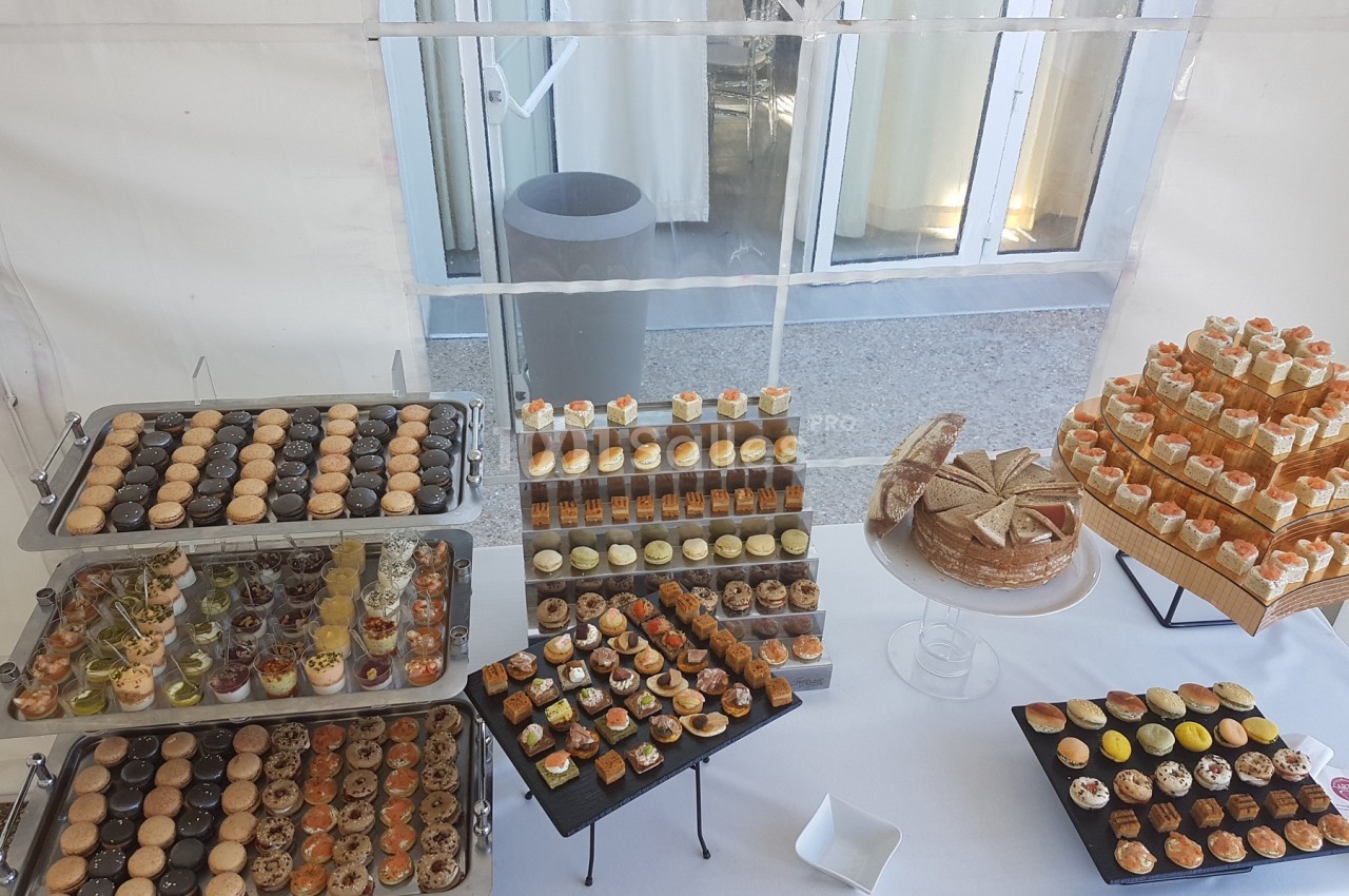 Buffet de desserts variés comprenant macarons, verrines, gâteaux et pâtisseries disposés sur des plateaux et présentoirs.