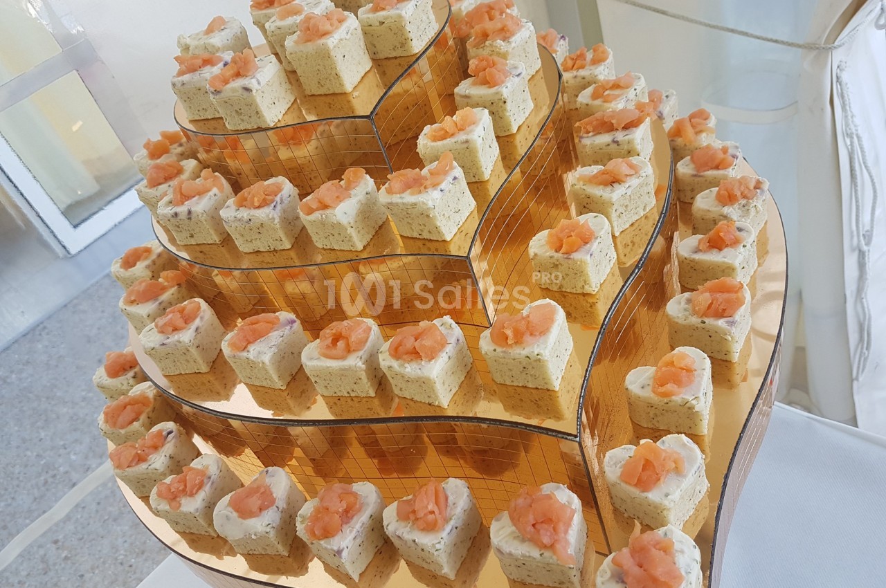 Plateau de bouchées apéritives en forme de cœur, garnies de mousse et de saumon, disposées sur plusieurs étages.