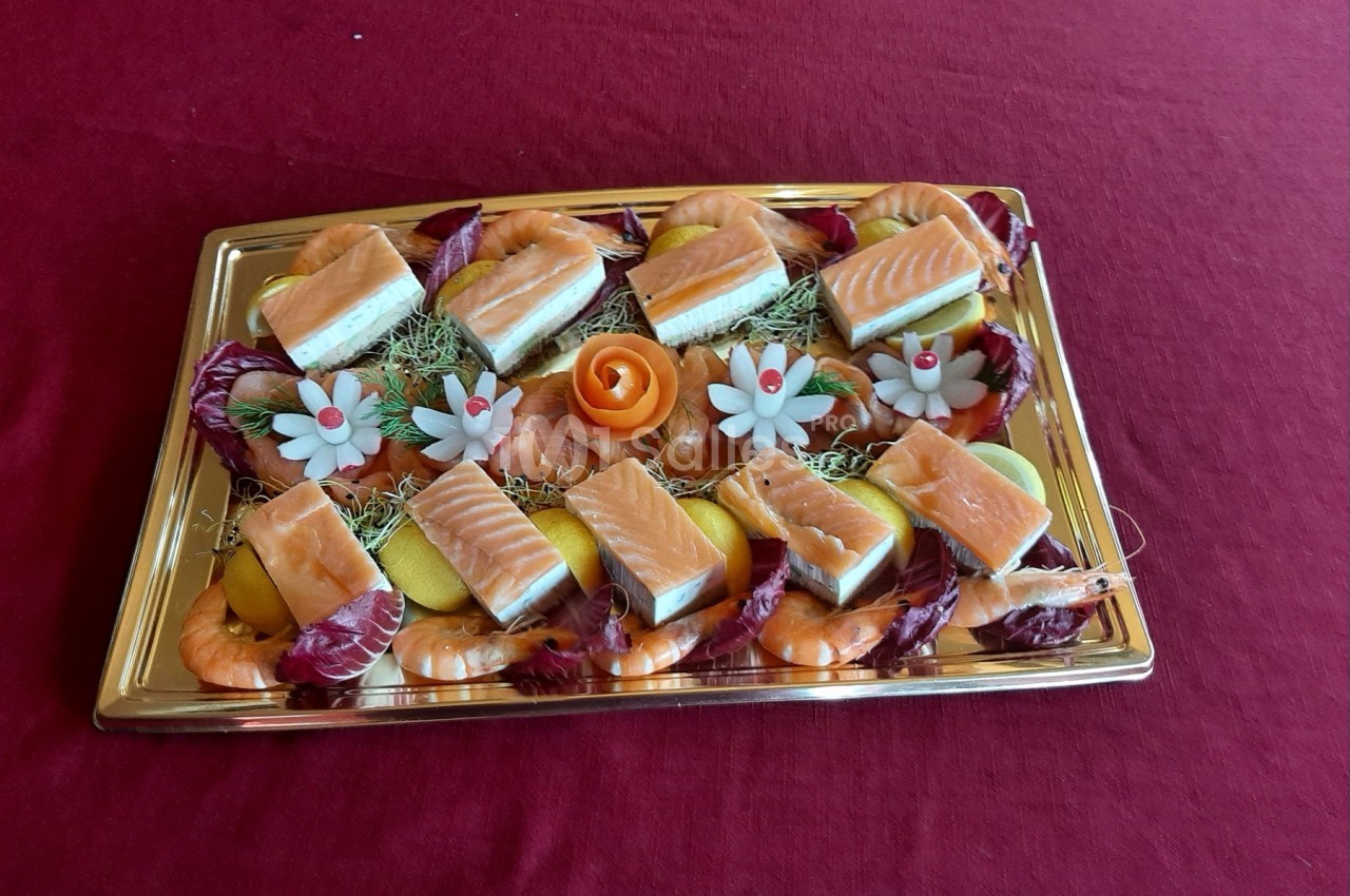 Plateau de saumon, crevettes, tranches de citron et décorations florales comestibles sur une nappe rouge.