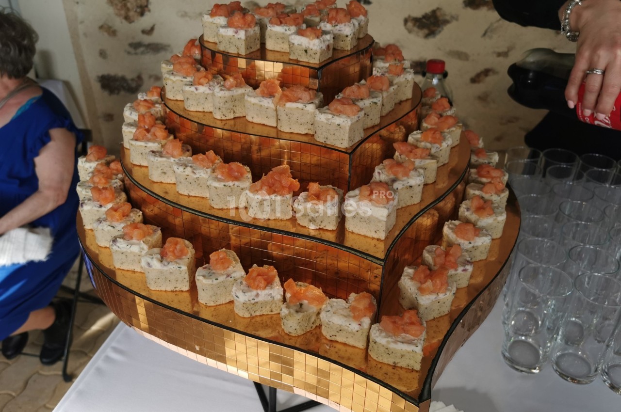 Plateau de pièces montées salées sur plusieurs étages, garnies de mousse et de saumon, présenté sur une table.