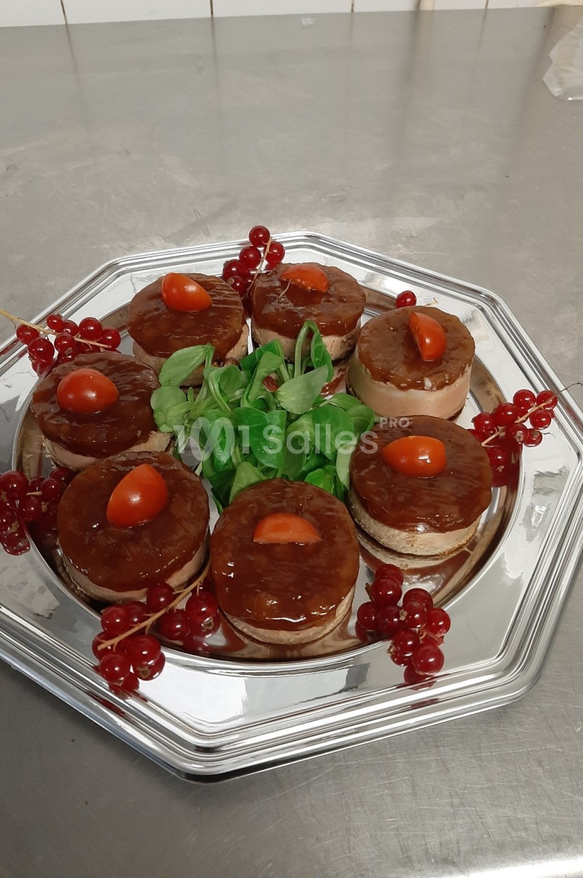 Plateau de petits desserts circulaires garnis de tomates cerises, entourés de groseilles et de feuilles vertes.