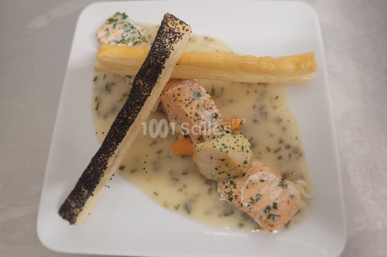 Assiette de saumon et noix de Saint-Jacques nappés de sauce, accompagnés de feuilletés garnis de graines de pavot.