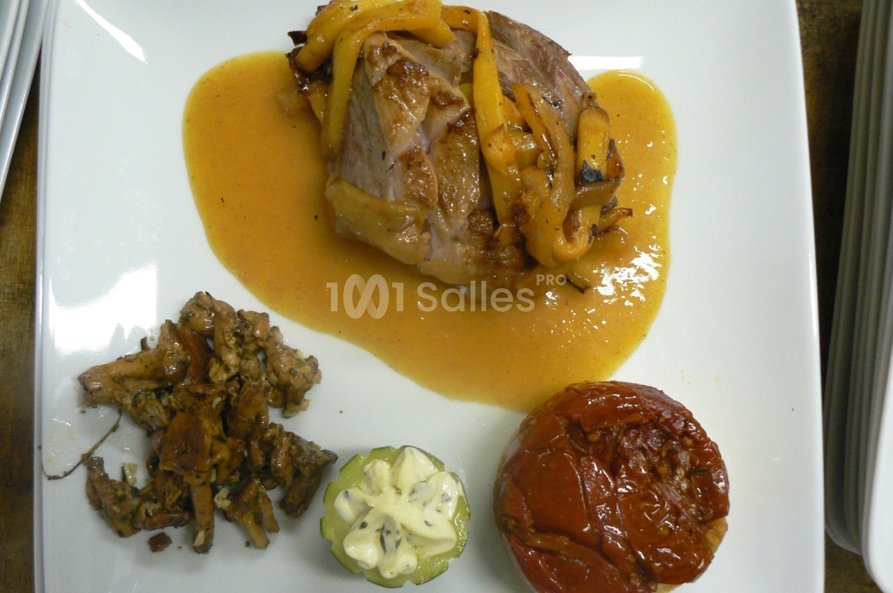 Assiette avec un morceau de viande en sauce, poêlée de champignons, tomate rôtie et courgette farcie.