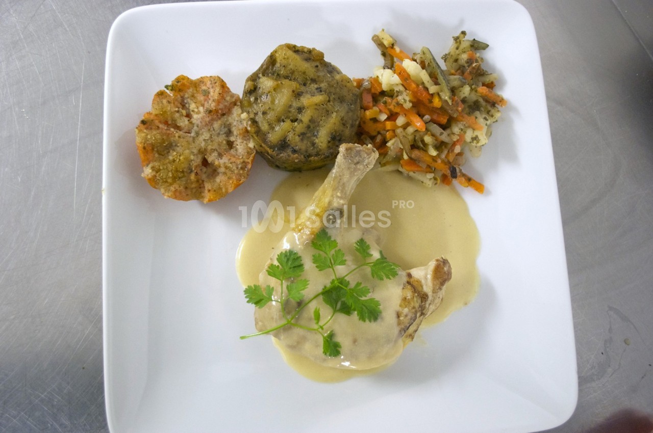 Assiette contenant une cuisse de volaille en sauce, accompagnée de légumes variés et de gratins individuels.