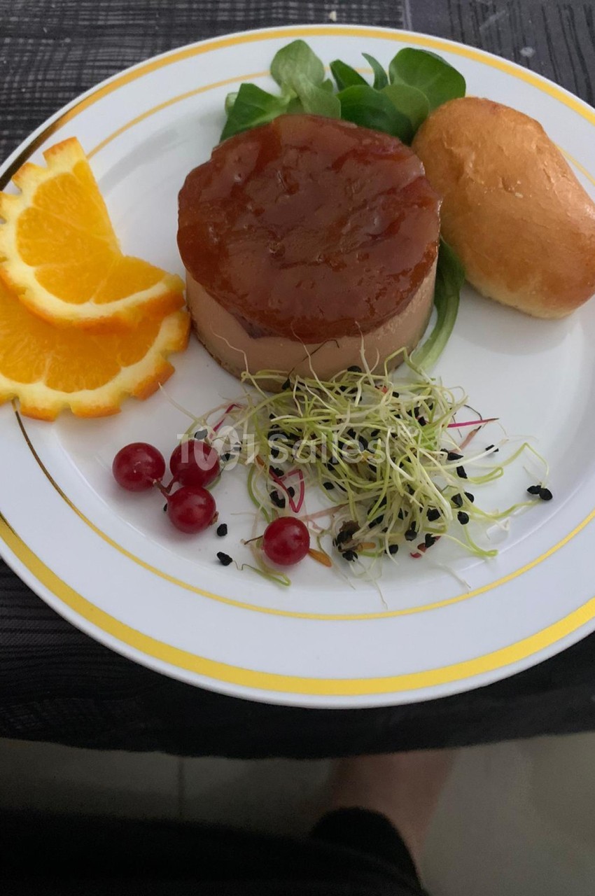 Assiette composée de foie gras, confiture, salade, rondelles d'orange, groseilles, pousses germées et pain brioché.