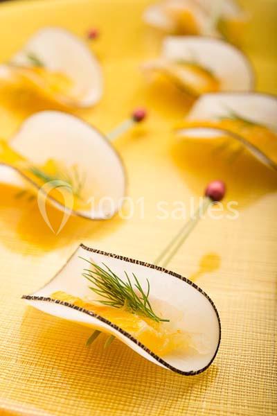 Tranches fines de poire garnies de fromage et d'aneth, présentées sur des piques en bois sur une nappe jaune.