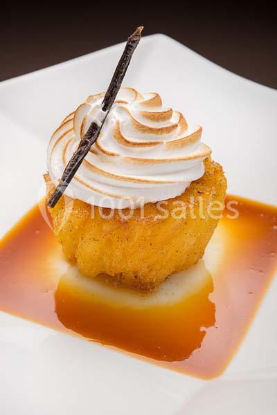 Dessert composé d'une brioche caramélisée, surmontée de meringue dorée et décorée d'une gousse de vanille.