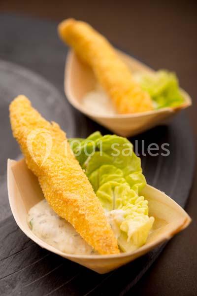 Bouchées de poisson pané servies sur un lit de laitue avec une sauce crémeuse dans des coupelles en bois.