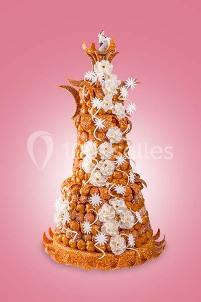 Pièce montée en choux caramélisés et décorations en sucre sur fond rose.