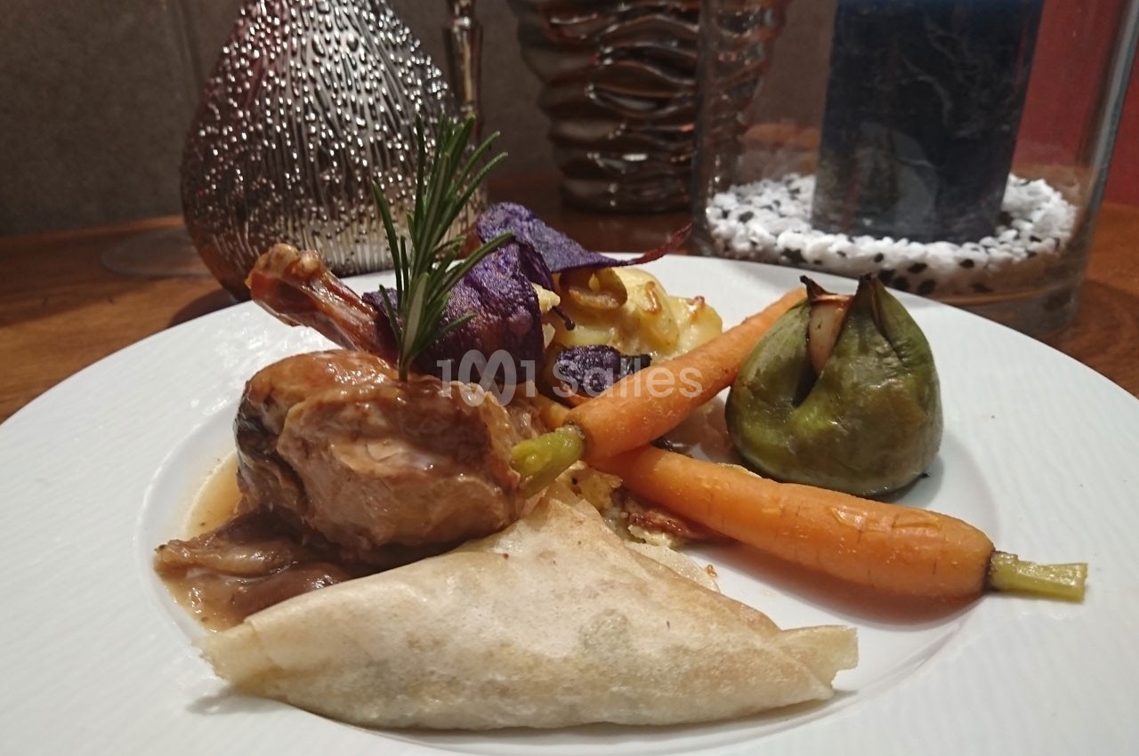 Assiette gastronomique composée de viande en sauce, légumes variés, samoussa et décoration raffinée.