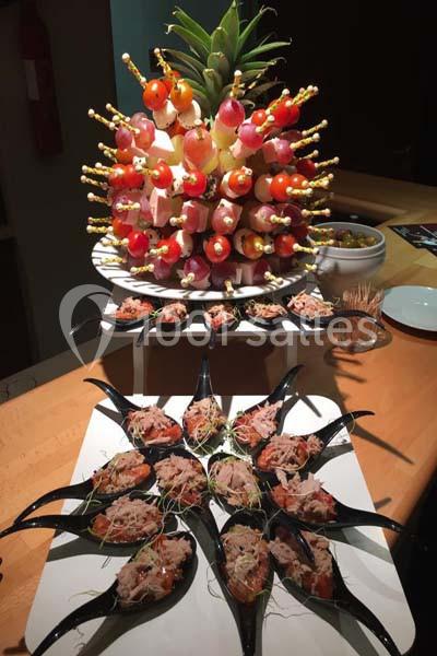 Brochettes de fruits sur un ananas décoratif et cuillères apéritives garnies de thon et pousses vertes.
