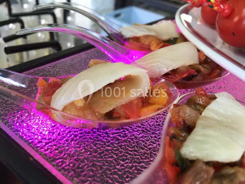 Cuillères transparentes contenant des bouchées de légumes colorés et de fines tranches de poisson blanc.