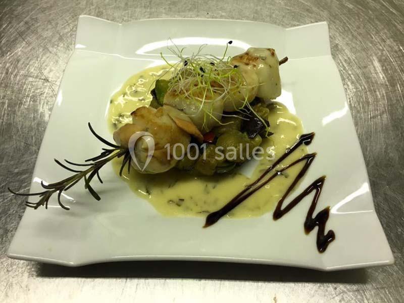 Brochette de fruits de mer sur lit de légumes, nappée de sauce crémeuse et décorée de pousses et de filet de balsamique.