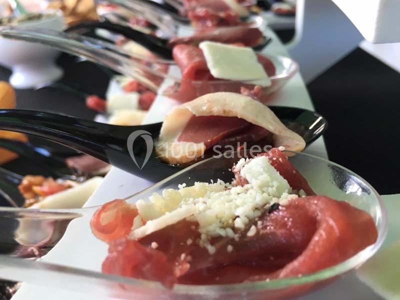 Tranches de viande crue et copeaux de fromage présentés sur des cuillères individuelles pour un service apéritif.
