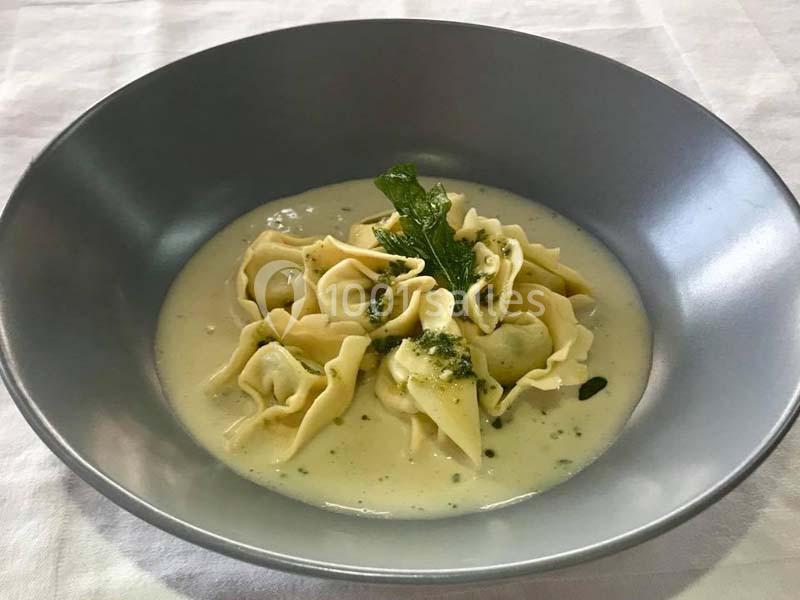 Assiette de raviolis garnis, servis dans une sauce crémeuse et décorés de feuilles de menthe.