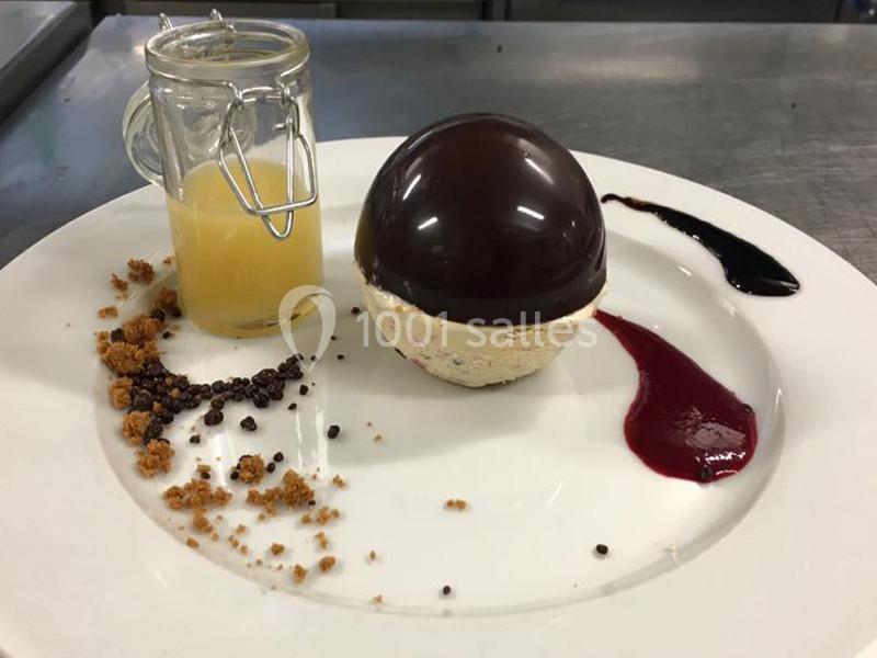 Dessert raffiné composé d'une mousse, d'un dôme chocolaté, d'un coulis, de miettes croquantes et d'une sauce en verrine.