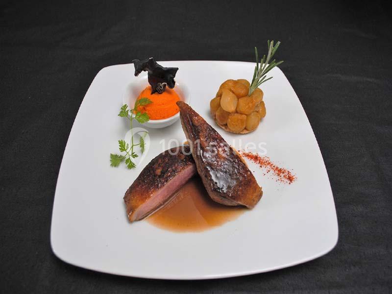 Assiette gastronomique avec magret de canard, purée orange, pommes de terre rôties et garniture d'herbes.