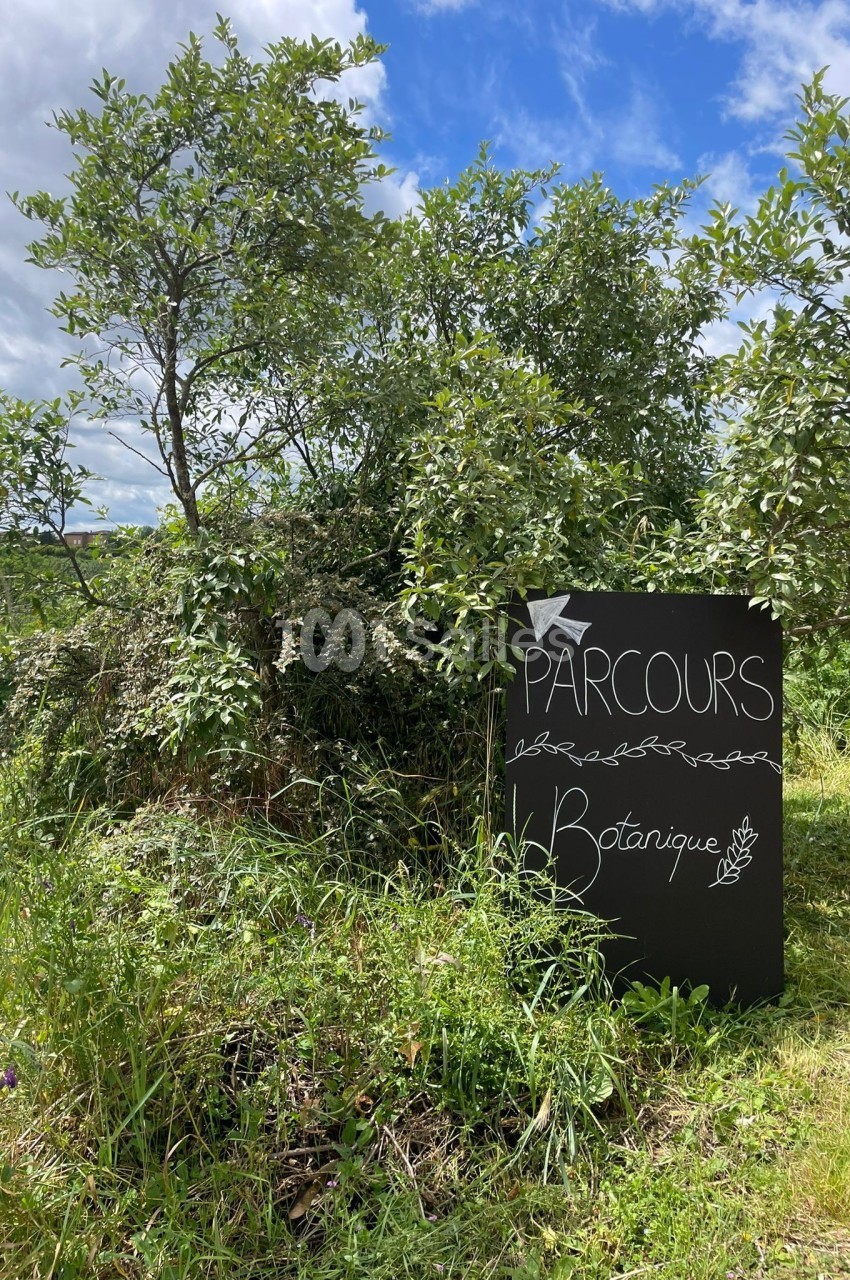 Panneau indiquant un parcours botanique, placé devant des arbustes dans un environnement naturel.