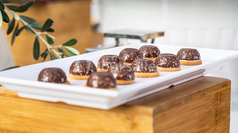 Assortiment de chocolats décorés sur un plateau blanc, posé sur une table en bois.