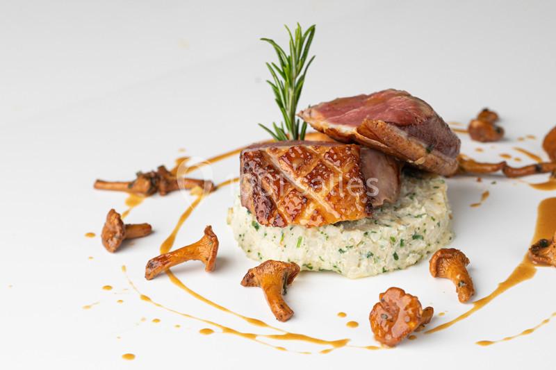 Plat gastronomique composé de magret de canard, purée aux herbes, girolles et sauce décorative.