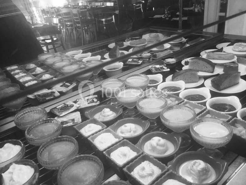 Vitrine présentant divers desserts et pâtisseries, dont des crèmes, tartes et gâteaux, dans un cadre de restaurant.