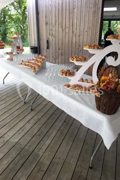 Buffet avec viennoiseries disposées sur des présentoirs en bois, table recouverte d'une nappe blanche sur une terrasse en…
