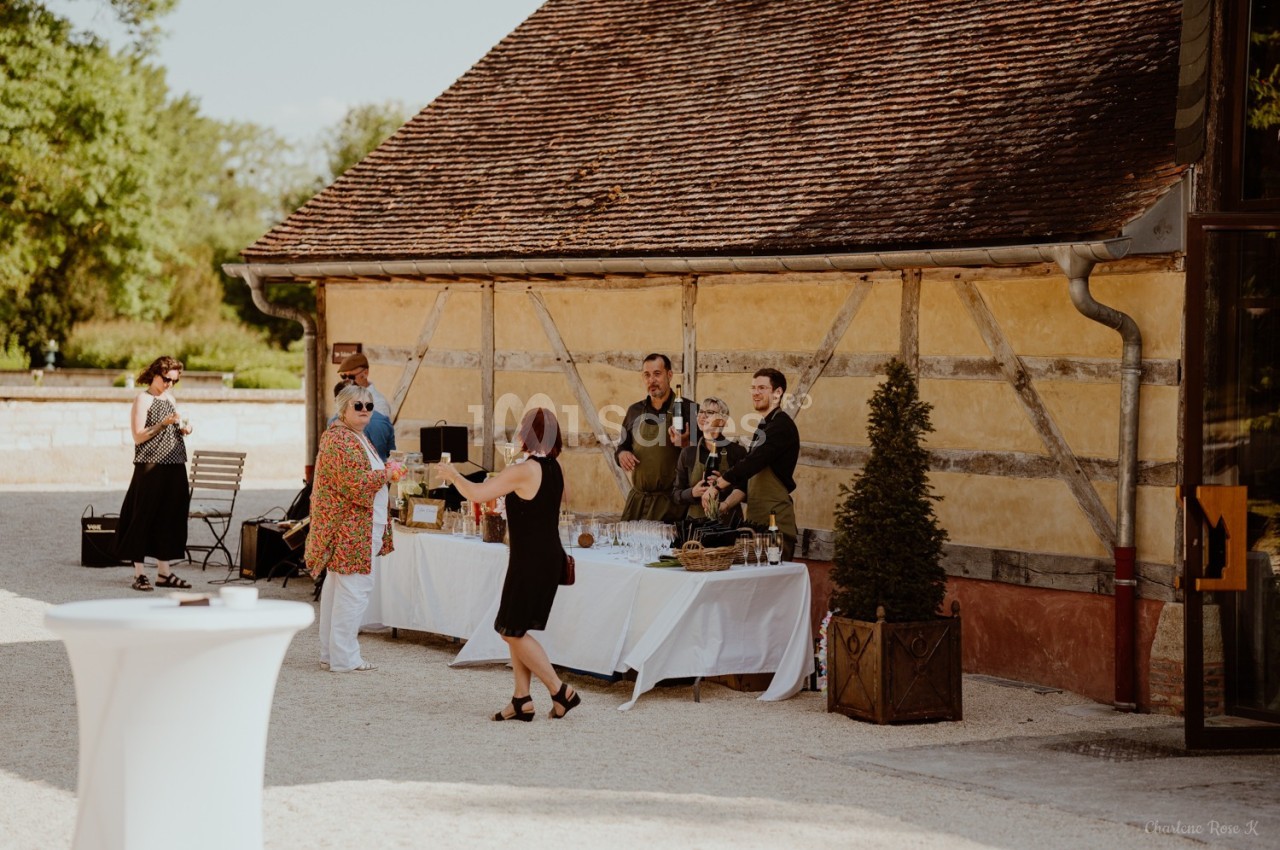 Un groupe de personnes près d'une table de buffet en extérieur, devant un bâtiment à colombages.