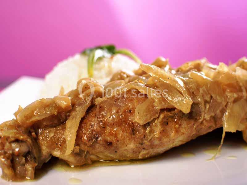 Plat de poulet mijoté avec des oignons caramélisés, accompagné de riz blanc, sur un fond rose.