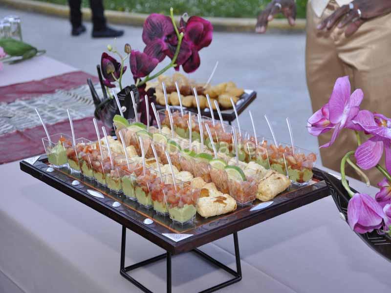 Plateau de verrines et amuse-bouches variés disposés sur une table décorée avec des fleurs violettes.