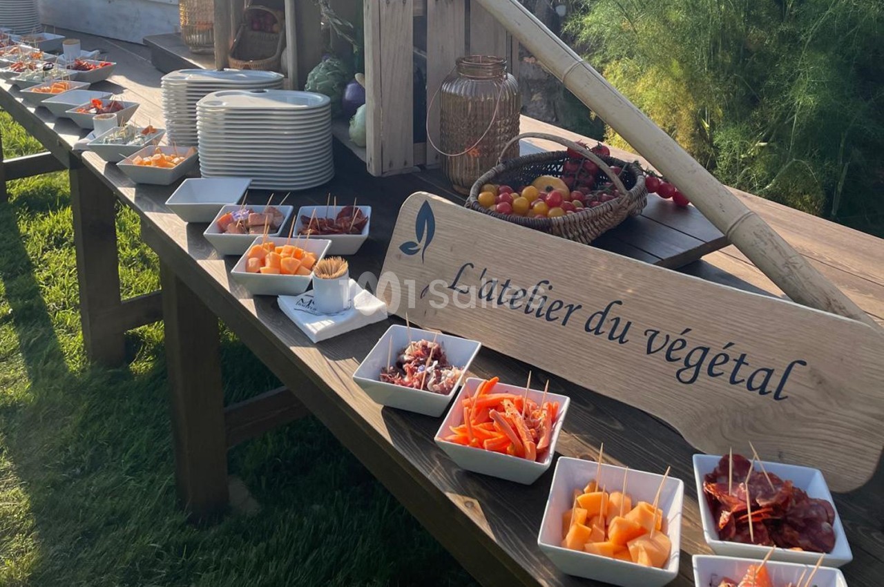 Buffet en plein air avec des assiettes de fruits, légumes et charcuteries disposées sur une table en bois.