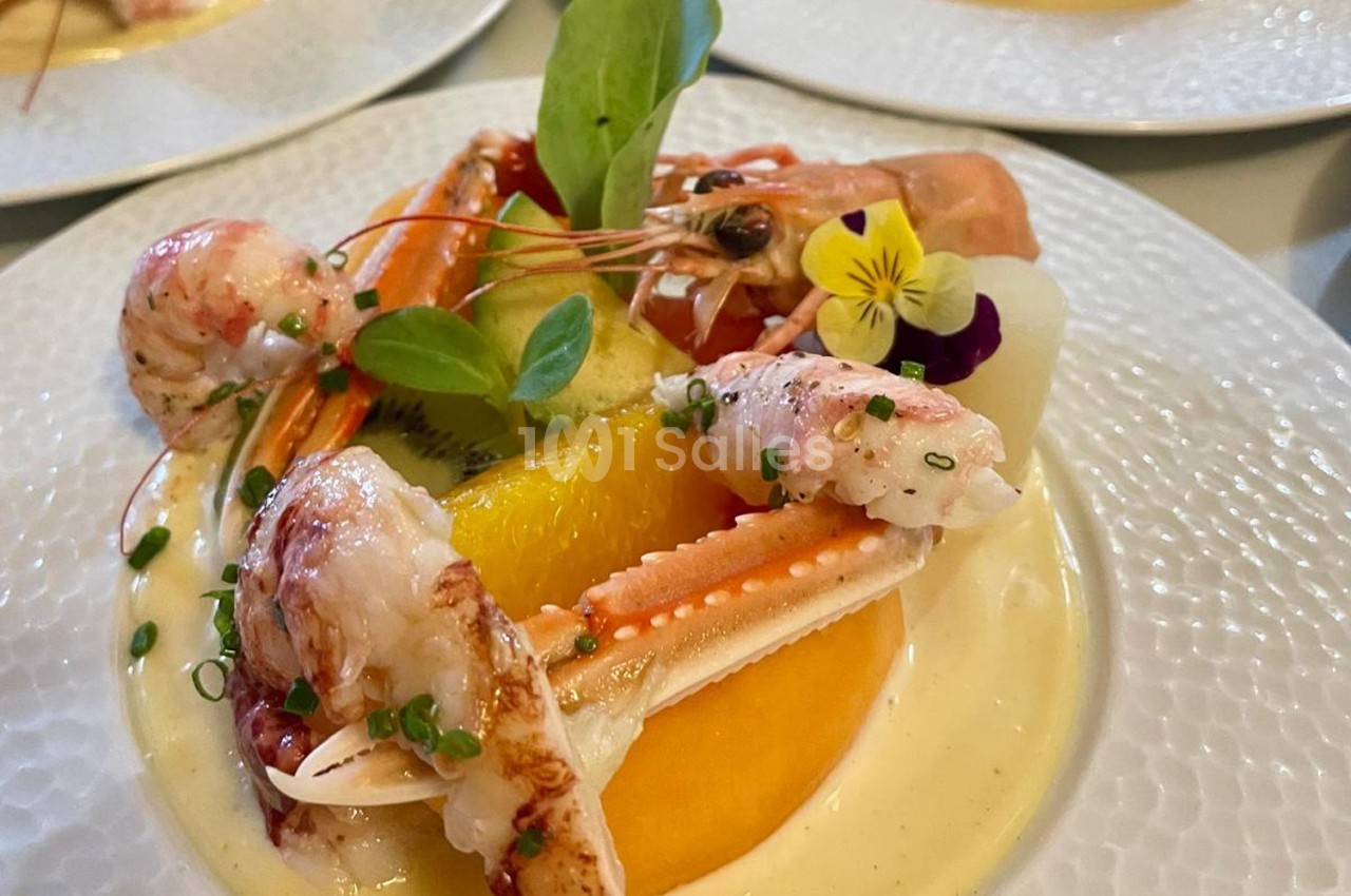 Assiette de fruits de mer avec crevettes, pinces de crabe, agrumes, herbes fraîches et une fleur comestible.