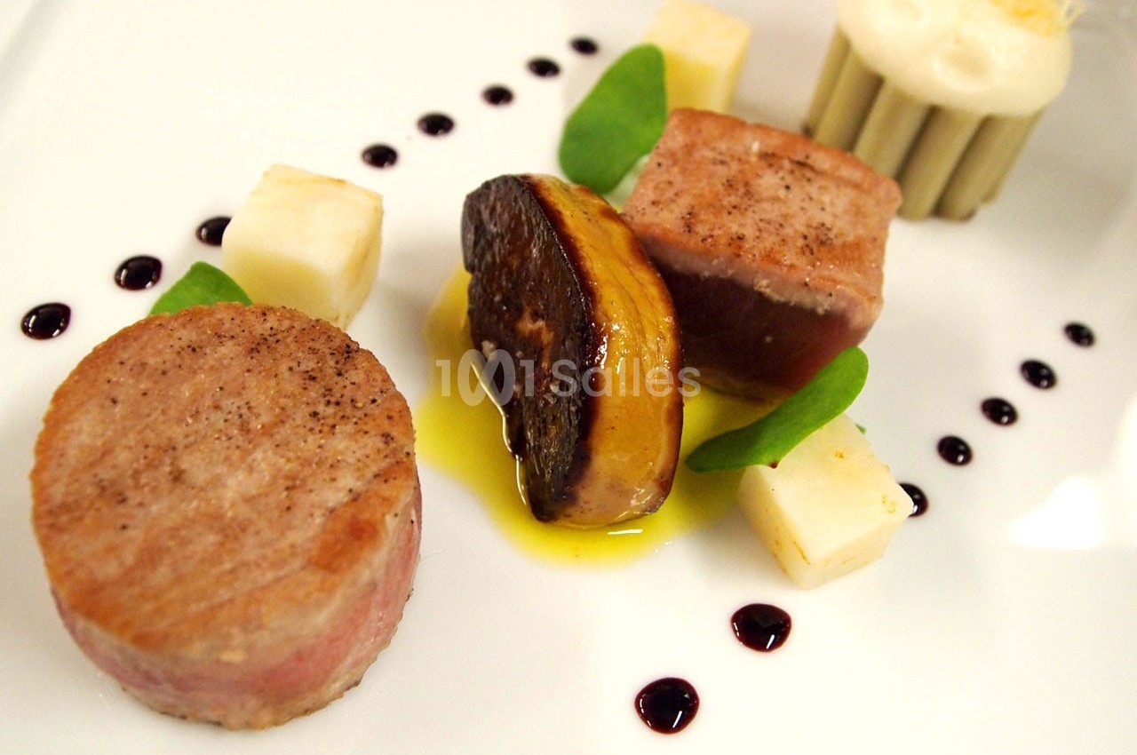 Assiette gastronomique composée de viande, foie gras, cubes de fromage, sauce et décorations de gouttes de réduction.
