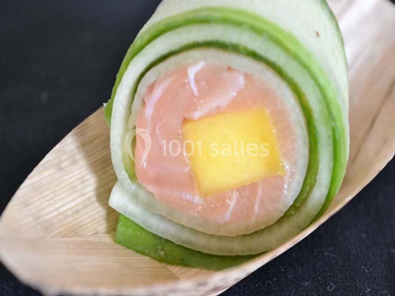 Rouleau de saumon, mangue et concombre présenté sur une petite assiette en bois.