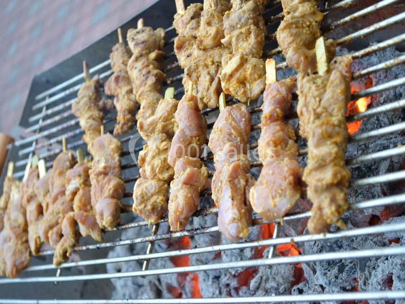 Brochettes de viande marinée grillant sur un barbecue au charbon de bois.