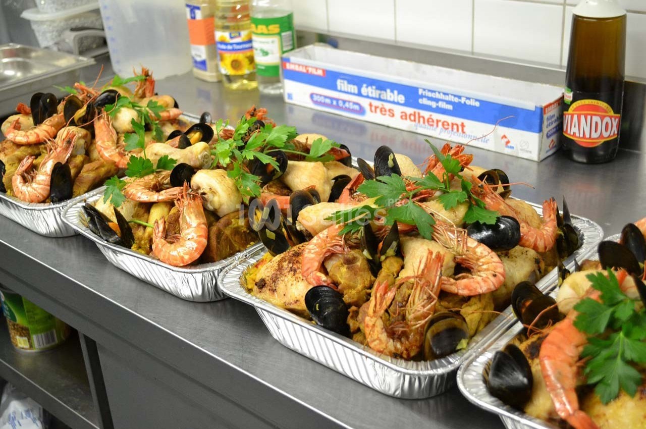 Plateaux de fruits de mer garnis de crevettes, moules, poissons et herbes fraîches, disposés sur un plan de travail en…