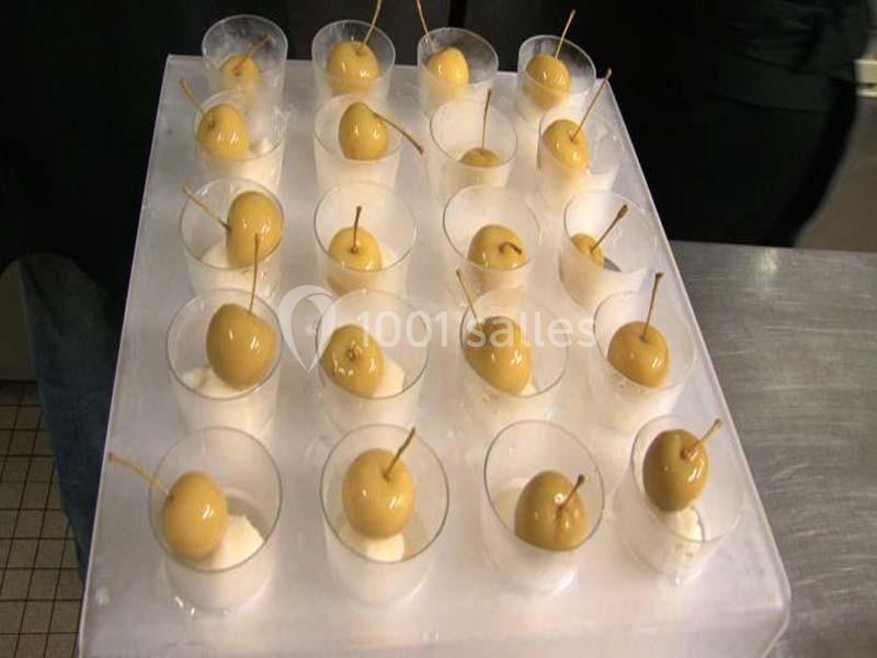 Des verrines contenant des boules dorées sur une base blanche, alignées sur un plateau transparent.