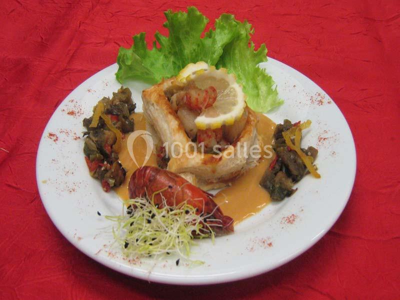 Assiette garnie d'un feuilleté au poisson, légumes sautés, sauce orange, citron, salade verte et germes décoratifs.