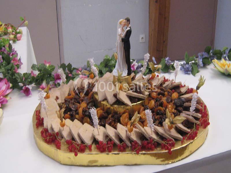 Plateau de foie gras décoré avec des fruits secs, des groseilles et une figurine de mariés au centre.