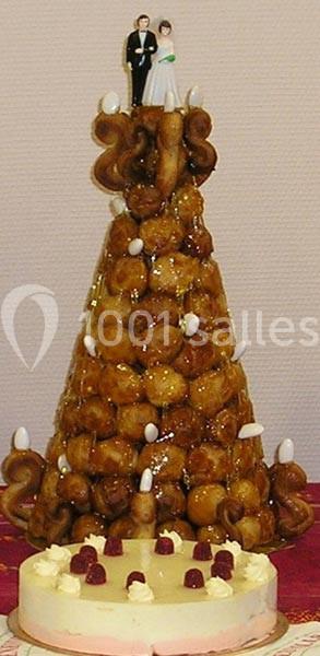 Pièce montée en choux caramélisés surmontée de figurines de mariés, accompagnée d'un gâteau décoré de fruits.