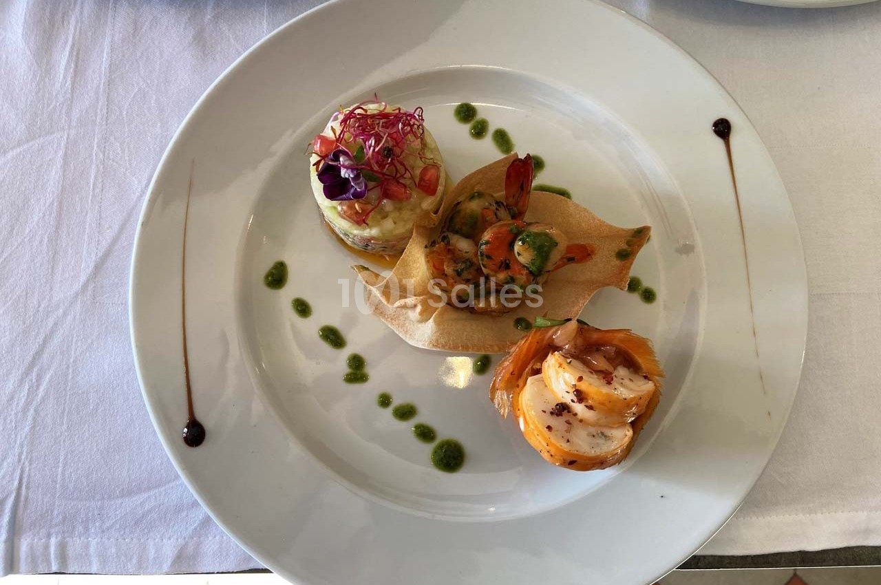 Assiette gastronomique composée de trois préparations raffinées, décorée de sauces et présentée sur une nappe blanche.