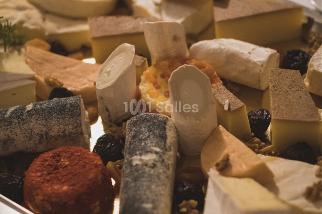 Plateau varié de fromages, comprenant des fromages à pâte dure, molle et persillée, accompagné de fruits secs.
