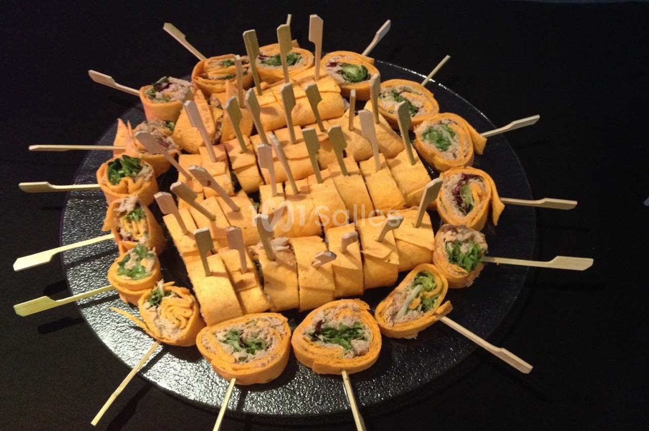 Plateau de wraps roulés garnis de légumes et viande, présentés sur des piques en bois sur une table noire.