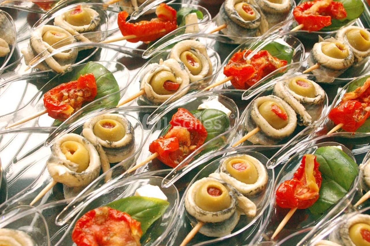 Assortiment de bouchées apéritives avec anchois, olives, tomates séchées et feuilles de basilic sur des cuillères…