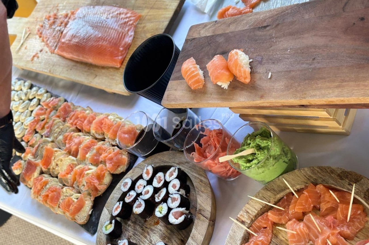 Plateau varié de sushis, sashimis et makis avec du saumon, du gingembre mariné et du guacamole sur une table.