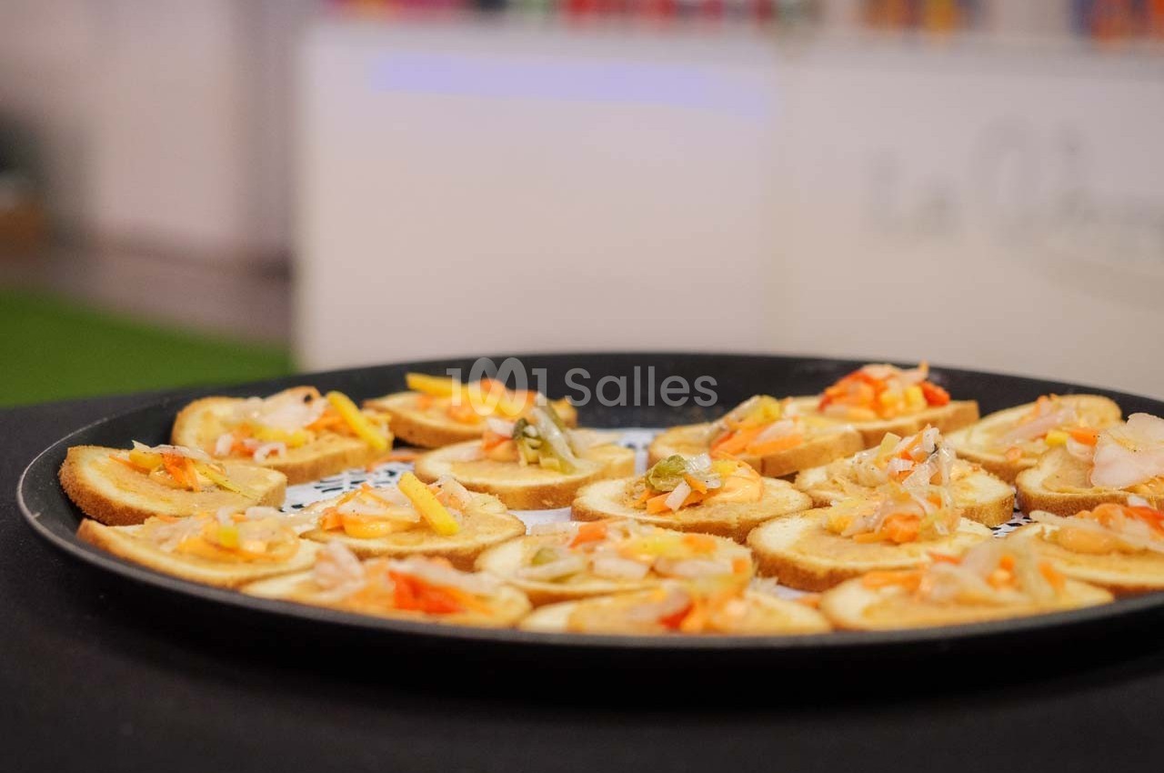 Plateau de toasts garnis de légumes colorés et de condiments, présenté sur une table noire.
