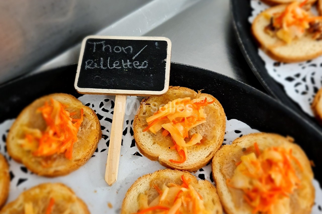 Toasts garnis de rillettes de thon et de légumes râpés, présentés sur un plateau avec une étiquette écrite à la main.