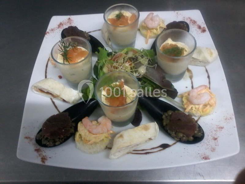 Assortiment de verrines, moules, crevettes et toasts garnis, présenté sur une assiette blanche avec salade.