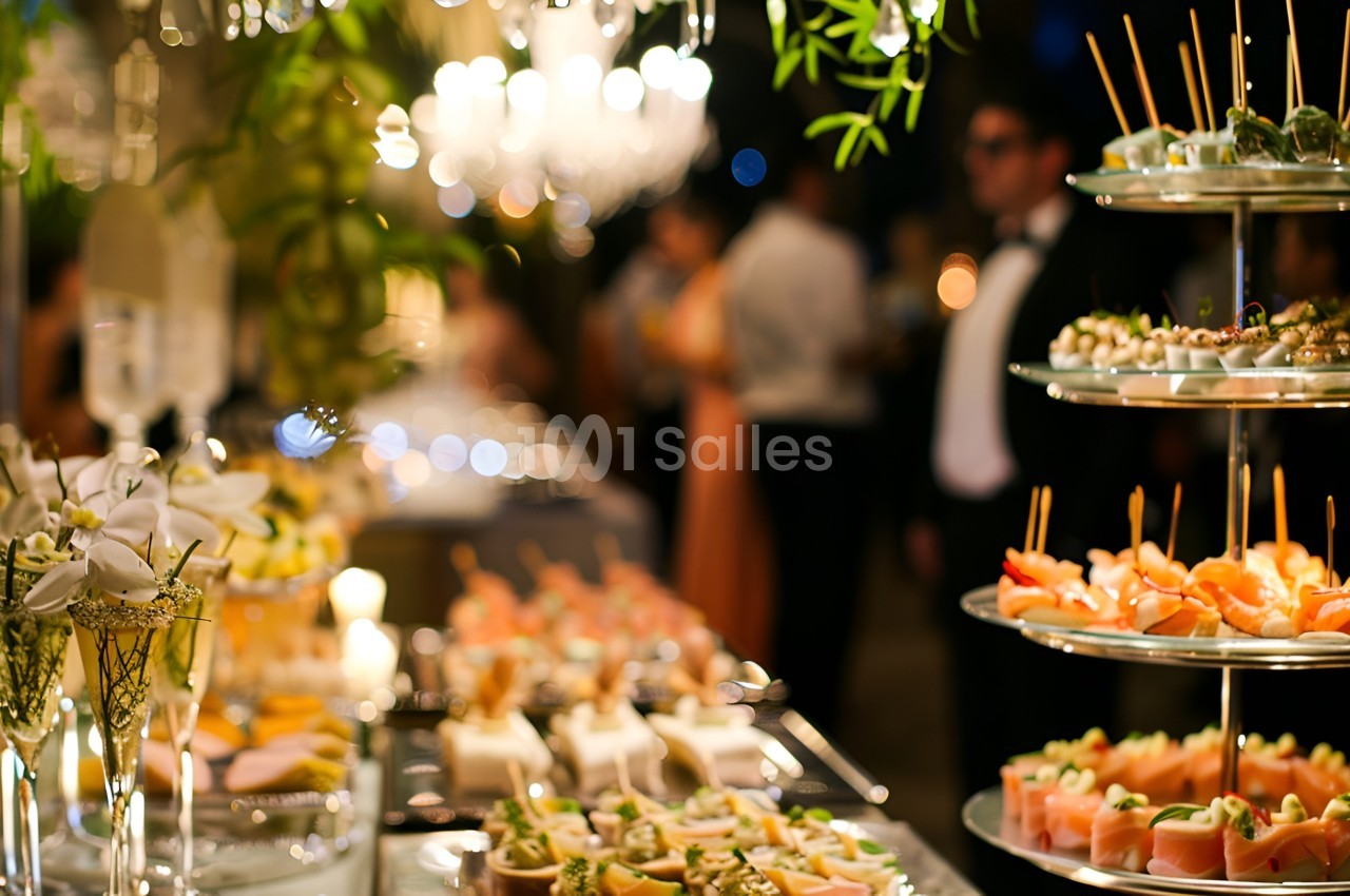 Buffet élégant avec divers amuse-bouches sur des plateaux, décoré de fleurs et éclairé par des lustres.